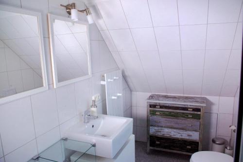 uma casa de banho branca com um lavatório e um espelho em Suite im Huus em Hamburgo