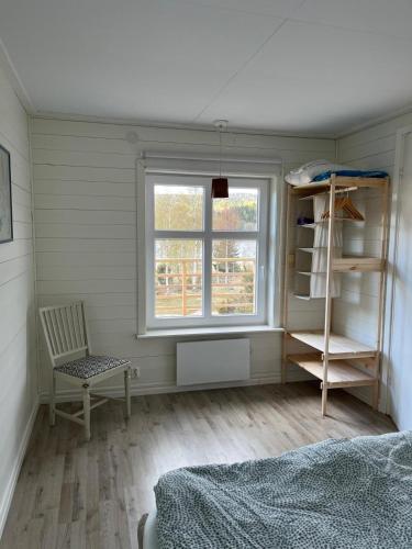 a bedroom with a bed and a window and a chair at Tiny House with ocean view in Näs