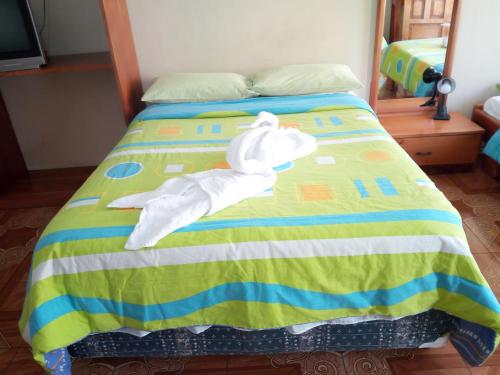 a stuffed white bird laying on a bed at Hostal Miconia in Puerto Ayora