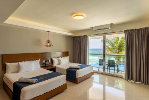 zwei Betten in einem Hotelzimmer mit Meerblick in der Unterkunft Ocean Dream Cancun by GuruHotel in Cancún