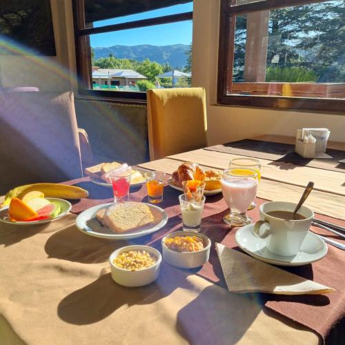 a table with breakfast foods and drinks on it at Berna Hotel & Spa in Villa General Belgrano