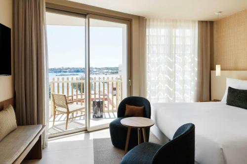 a hotel room with a bed and a balcony at Sabatic Formentera Autograph Collection in Es Pujols