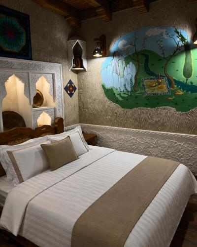 a bedroom with a large bed with a painting on the wall at Green City Hotel ШАХРИСАБЗ in Khujand