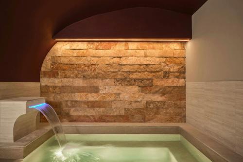 a swimming pool with a brick wall and a fountain at Hotel Urbana, a Tribute Portfolio Hotel in Rome