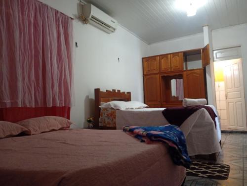 a bedroom with two beds and a window and a door at Pousada kurasi alter 02 in Santarém