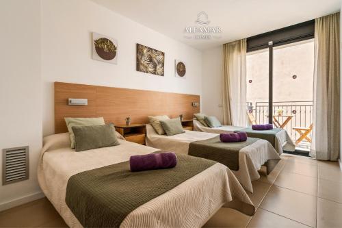 a hotel room with three beds and a balcony at Hanami Suite in Lloret de Mar