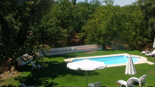 a swimming pool with an umbrella and a table and chairs at Hotel Apartamento Rural Finca La Media Legua in Aracena