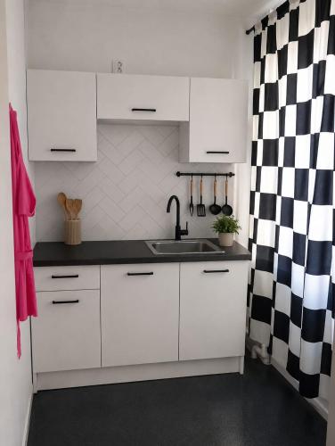 a kitchen with white cabinets and a black and white checkered curtain at Sercowe Zacisze in Chełmża