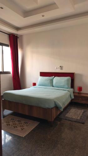 a bedroom with a large bed with a red curtain at Villas HouN Assinie in Mafia