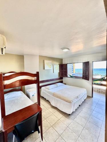 a bedroom with two beds and a desk and a window at Pousada Legno Bossa Nova in Maceió