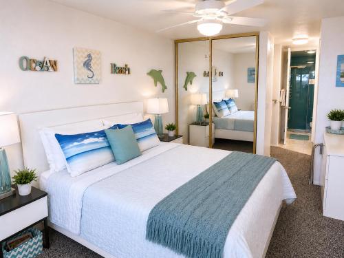 a bedroom with a large white bed with blue pillows at SolMar Breeze - 1BR Condo at North Coast Village - Heated Pools, Hot Tubs & Steps to Beach, Oceanside Harbor and Pier in Oceanside
