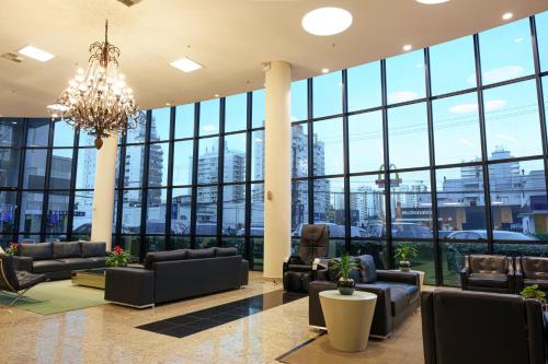 a lobby with couches and chairs and a chandelier at Firenze Business Hotel in Palhoça