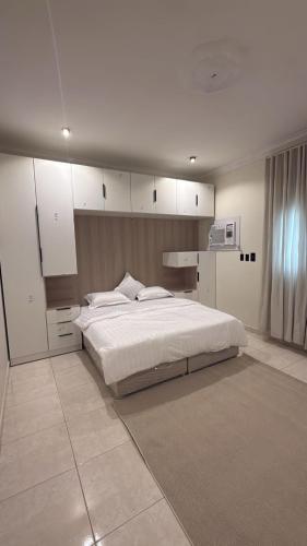 a bedroom with a large white bed and white cabinets at شقق وهل in Dammam
