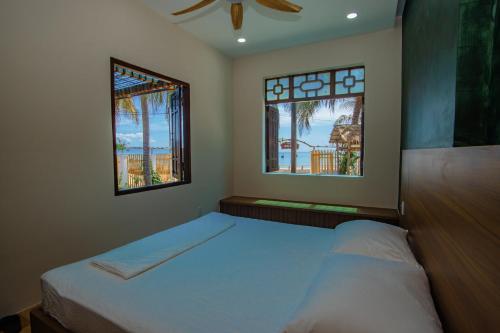 a bedroom with two beds and two windows at 4be Cá Heo in Cầu Sông Kinh