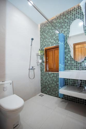 a bathroom with a toilet and a green tiled wall at 4be Cá Heo in Cầu Sông Kinh