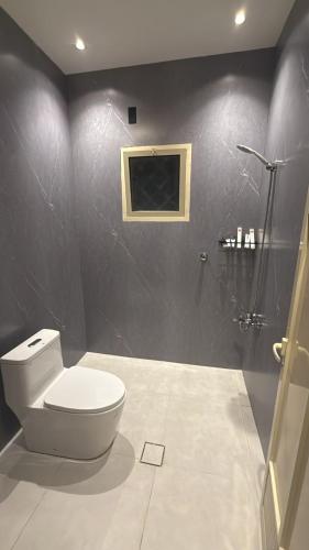 a bathroom with a white toilet and a shower at شقق وهل in Dammam