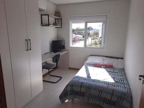 a bedroom with a bed and a desk and a window at Meu lar na Serra Gaúcha in Nova Petrópolis