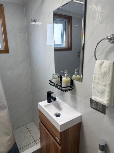 a white bathroom with a sink and a mirror at Casa monje Patagonia in Puerto Natales