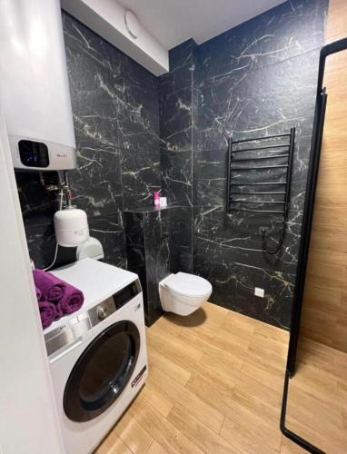 a washing machine in a bathroom with a toilet at Modern apartment in Klaipėda