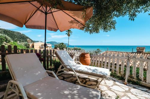 two chairs and an umbrella on a patio with the ocean at Corfu Glyfada Beach Apartment 24 in Glyfada