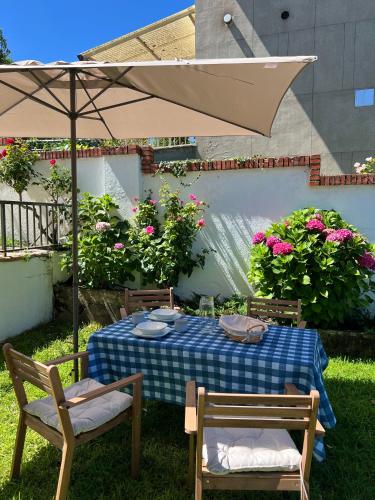ein Tisch mit Sonnenschirm, zwei Stühlen und Blumen in der Unterkunft La Almendrina Casa Rural in Villafranca del Bierzo
