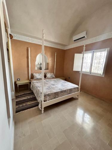 a bedroom with a four poster bed and a window at maison rachid in El Guecheïne