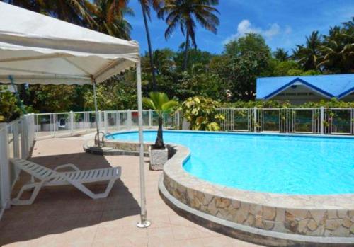 ein Schwimmbecken mit einem Stuhl und einem Sonnenschirm in der Unterkunft Hotel Le Rotabas in Sainte-Anne