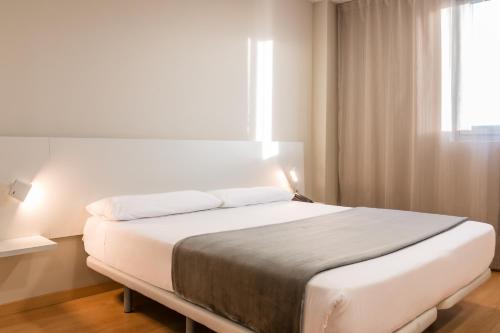 a hotel room with a large bed and a large window at Vértice Roomspace in Madrid