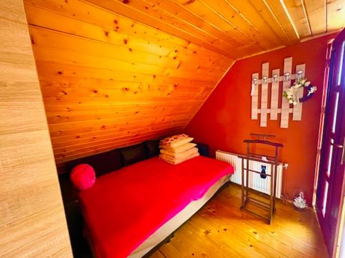 a room with a red bed in a wooden room at Solaris Apartman Ráckeve in Ráckeve