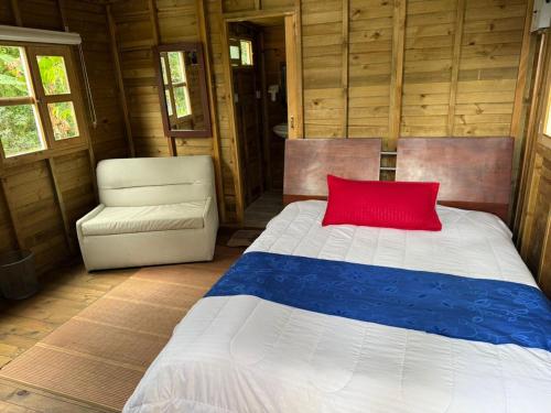 a bedroom with a bed with a red pillow and a chair at Cabañas Creation Garden - Espacio de Vida Saludable in San Francisco