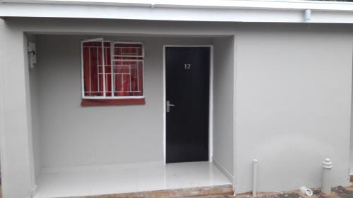 a white building with a black door and a window at Valley Guest House in Pretoria