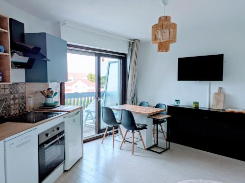 a kitchen with a table and chairs and a kitchen with a balcony at L'évasion Marine in Camiers
