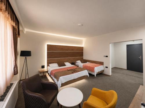 a hotel room with two beds and a table and chairs at Semberski Salaš Intergaj Hotel in Bijeljina