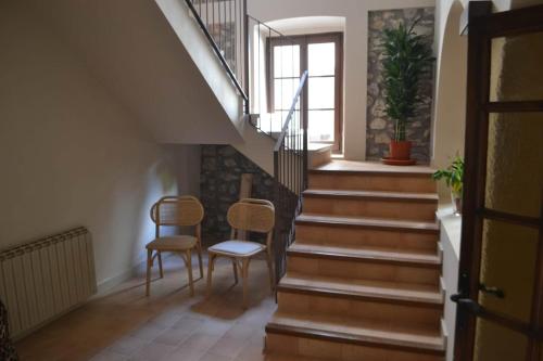 a hallway with stairs with two chairs and a window at Can Hortafa in Tortellá