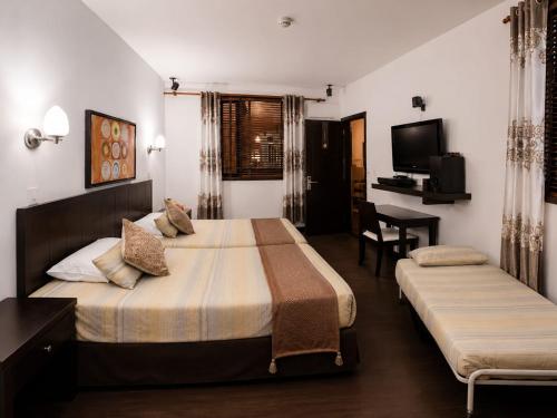 a hotel room with two beds and a desk at hostal cf bed y breakfast in Cali