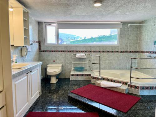 a bathroom with a tub and a toilet and a window at Casa Hidalgo Ecuador in Cumbayá