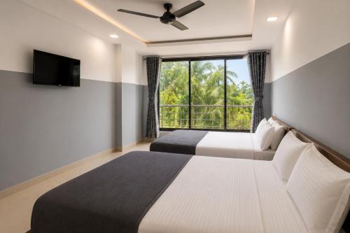 two beds in a room with a large window at SAVRAJ Stay Beach Goa in Candolim