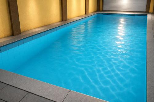 a large blue swimming pool in a building at SAVRAJ Stay Beach Goa in Candolim