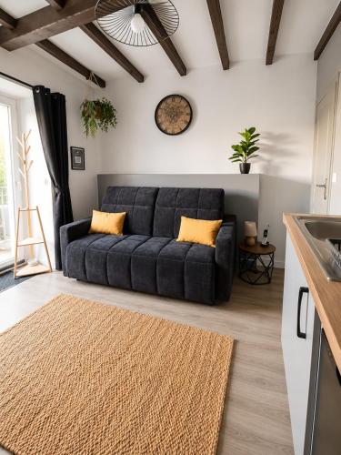 a blue couch in a living room with a clock on the wall at Le Bourg - Studio 2pers -Climatisation et terrasse in Bourg-lès-Valence