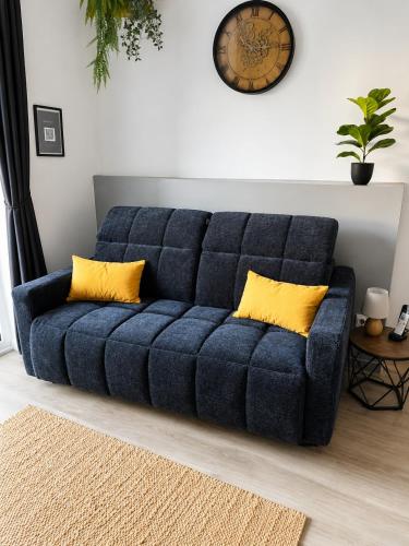 a blue couch with yellow pillows in a living room at Le Bourg - Studio 2pers -Climatisation et terrasse in Bourg-lès-Valence
