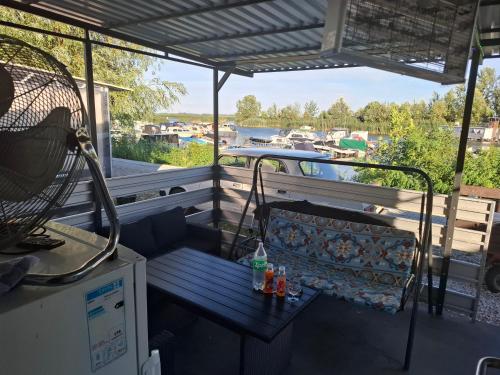 a bench on a porch with a view of a boat at Cuki Apartmanház in Sarud