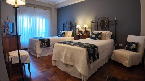 a bedroom with two beds and a chair at Solar De La Plaza in Salta