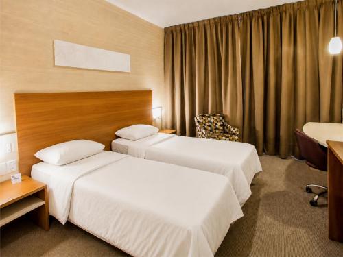 a hotel room with two beds and a chair at Swan Novo Hamburgo in Novo Hamburgo