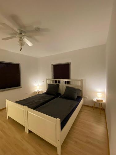 a bedroom with a white bed and two windows at Ferienwohnung Burgstadt Kastellaun in Kastellaun