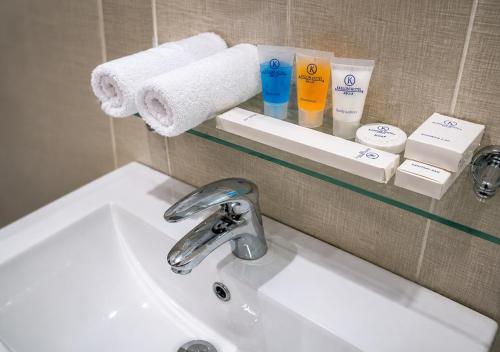 a bathroom sink with towels on a shelf above it at Kaslon Hotel, Garki 2 Abuja in Abuja