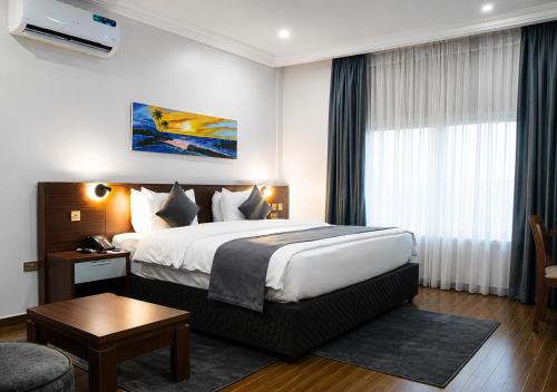 a hotel room with a large bed and a table at Kaslon Hotel, Garki 2 Abuja in Abuja