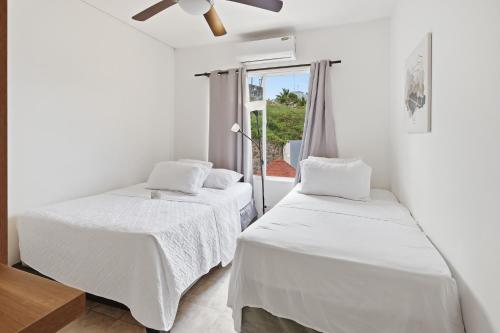 two beds in a white room with a window at Casa Docia Hotel in Santa Bárbara de Samaná
