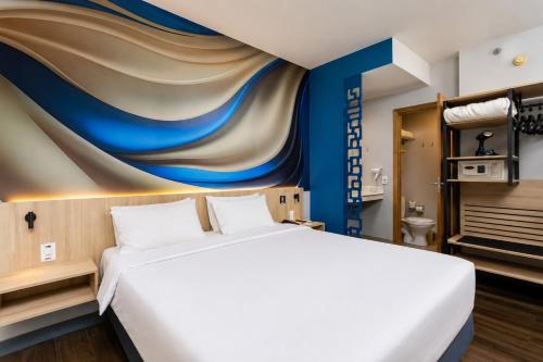 a bedroom with a large bed and a painting on the wall at Comfort Hotel Joinville in Joinville