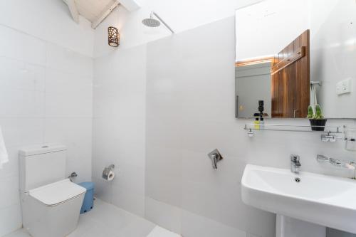 a white bathroom with a toilet and a sink at Arches Fort in Galle