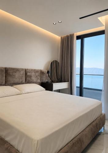 a bedroom with a large bed and a large window at IDeal Sea View Apartment in Vlorë